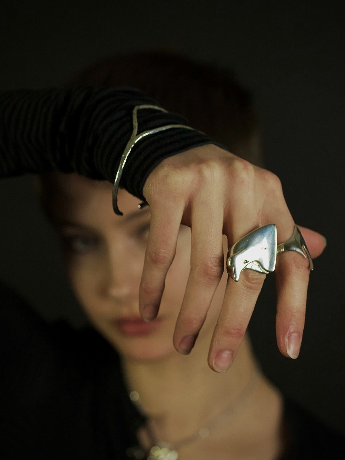 A model holds up a hand wearing the Reflection ring and the Split bracelet